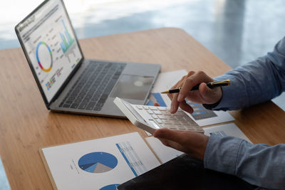 Midsection of man using laptop on table