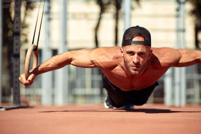 Portrait of shirtless man exercising in gym