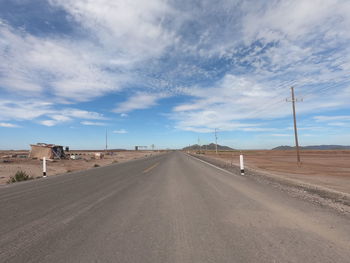 Empty road amidst desert against sky