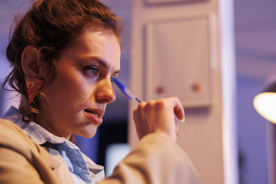 Side view of young woman applying make-up at home