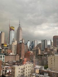 Buildings in city against cloudy sky