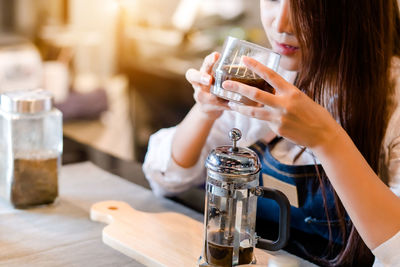 Midsection of woman drinking glass on table