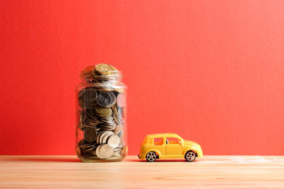 Toy car on table against red background