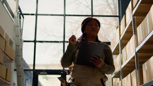 Portrait of young woman standing against building