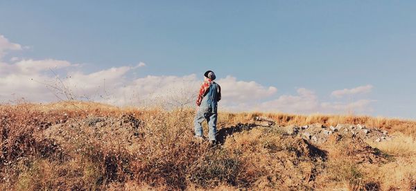 Rear view of man standing on land against sky