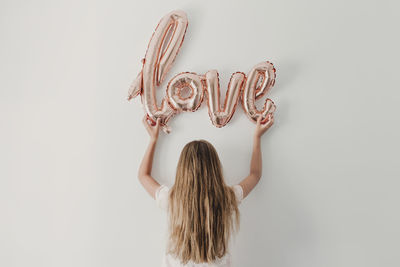 Rear view of woman holding painting against white background