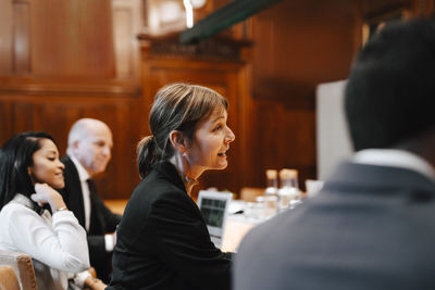 Smiling female lawyer in board room with colleagues during meeting