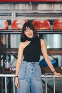 Portrait of smiling young woman standing against wall