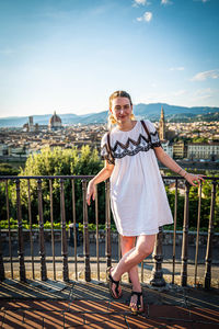 Portrait of smiling young woman standing against railing