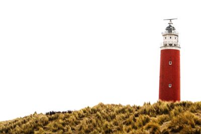 Lighthouse on field against sky