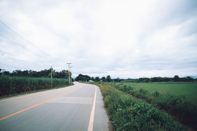 Road amidst field against sky