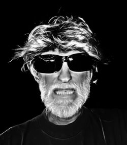 Portrait of man wearing sunglasses against black background