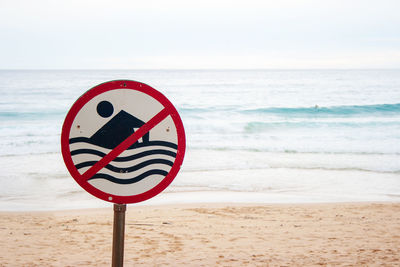 Sign on beach against sky