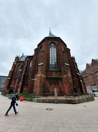 Man walking by historic building against sky