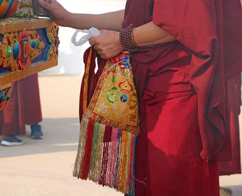 Midsection of monk holding bag