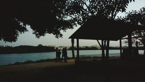 Silhouette people standing by lake against sky