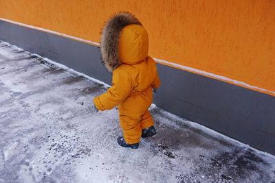 Full length of girl standing on snow covered wall