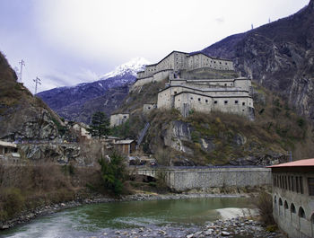 Bridge over river by buildings against sky