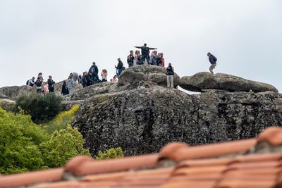 People on rock against sky