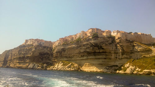 Scenic view of cliff and village against clear sky