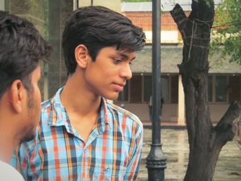 Close-up of friends standing against tree