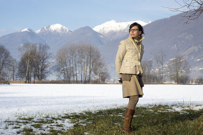 Woman standing on grass against mountains during winter