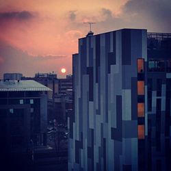 Buildings against cloudy sky at sunset