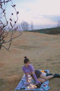 Side view of woman sitting on grassy field