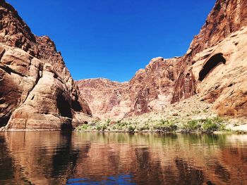Rock formations by lake against blue sky