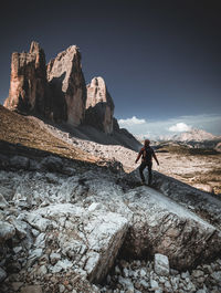Man standing on rock by mountain against sky