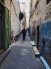 Man walking on footpath amidst buildings in city