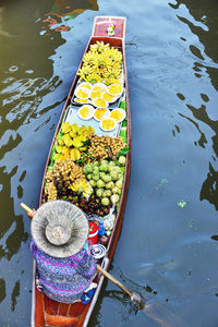 High angle view of woman with various food in boat sailing on river