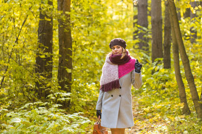 Woman standing by trees in forest