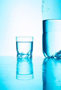 Close-up of water glass on table against blue background