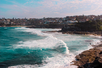 Scenic view of sea by cityscape against sky