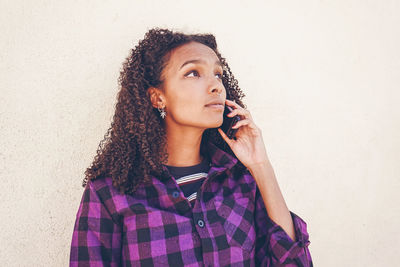 Portrait of beautiful young woman standing against wall