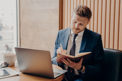 Businessman writing in diary at office