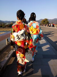 Rear view of women walking on mountain against clear sky