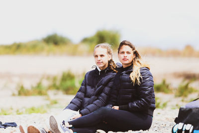 Portrait of smiling friends sitting on field
