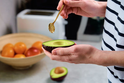 Woman hold fresh ripe avocado and peeling it with spoon, healthy food and dieting concept