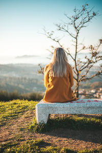 Rear view of woman sitting on rock