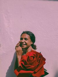 Portrait of a smiling young woman standing against wall
