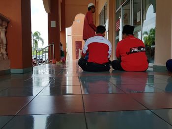 Rear view of people sitting on tiled floor in building