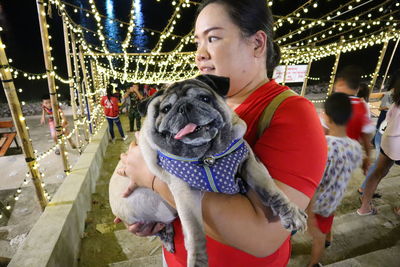 Woman carrying dog in illuminated city