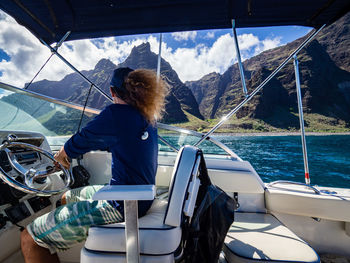 Man sitting in boat against mountains