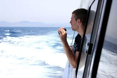 Man looking through window of van at beach