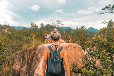 Rear view of man standing on mountain against sky
