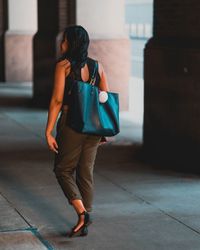 Full length rear view of woman walking on footpath