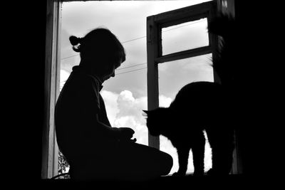 Silhouette woman standing by window at home