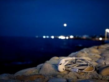 Close-up of rocks by sea against sky at night